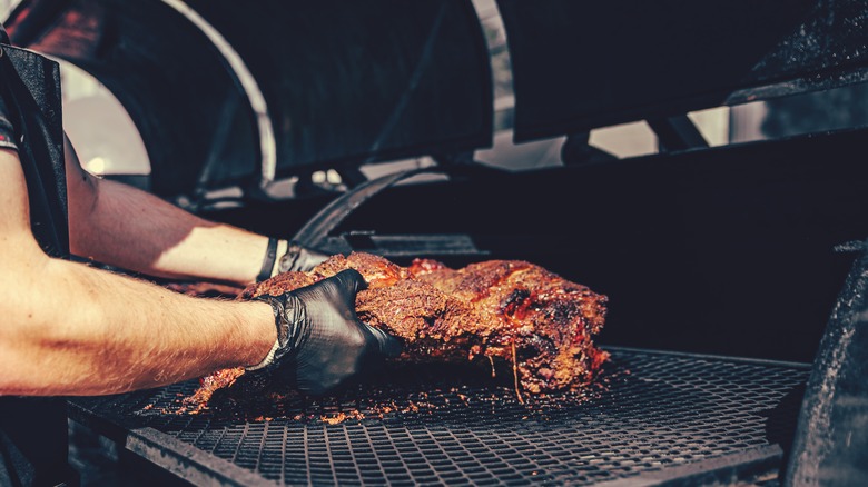 Person placing meat in a smoker