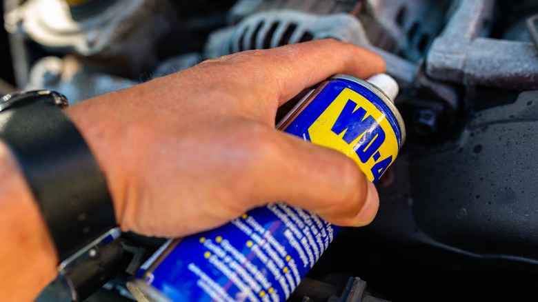 person spraying WD-40 in engine