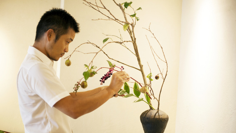 Man arranging branches in vase