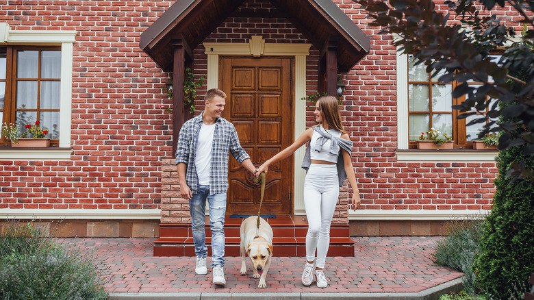 Couple with dog outside brick house