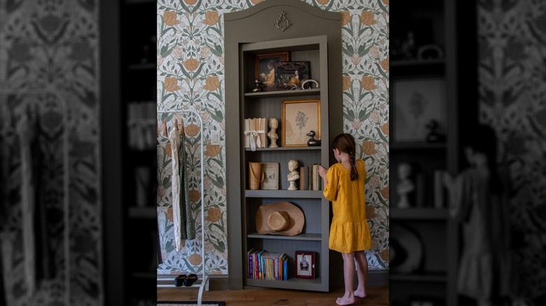 Young girl opening bookcase door