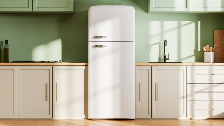 White fridge with green walls and white cabinets