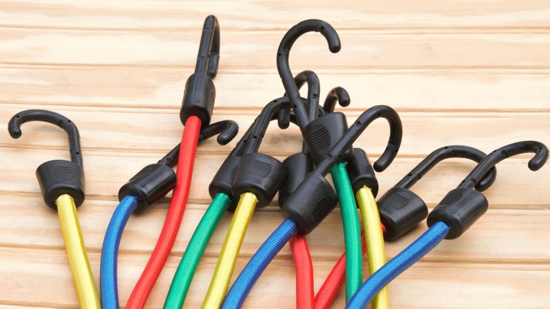 bundle of bungee cords in assorted colors lying on light wood beadboard