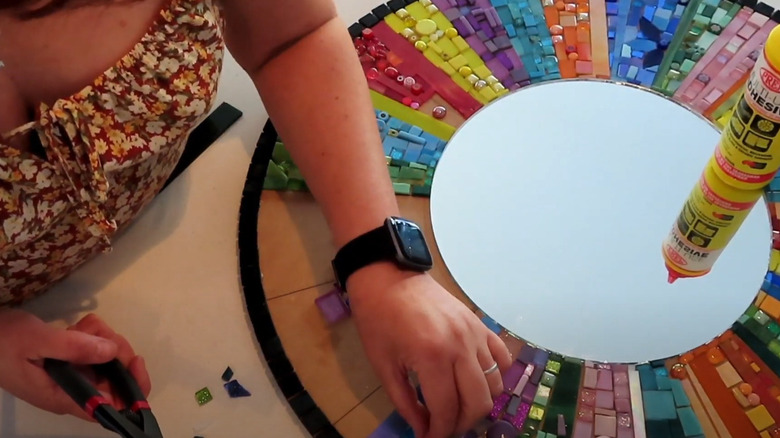 Woman making a DIY mosaic wall mirror.