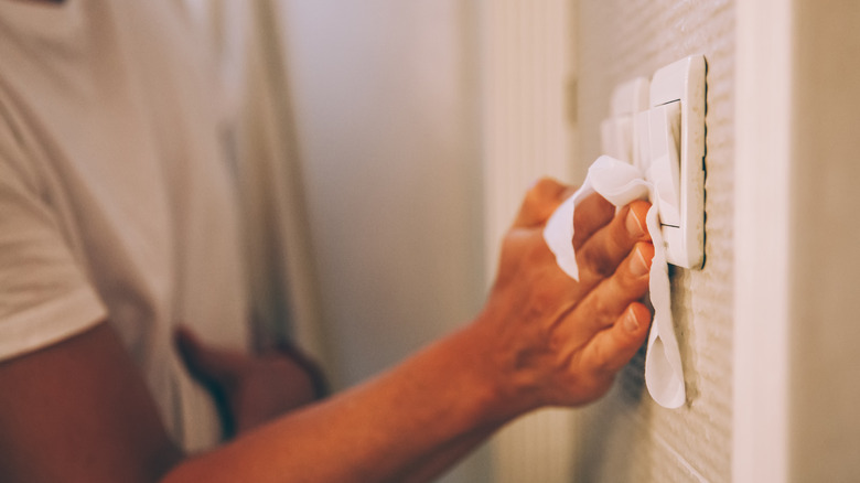 Person cleaning light switch