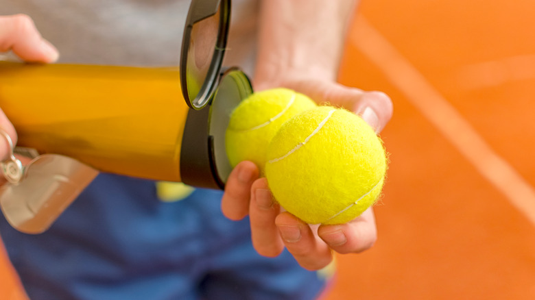 man opening tennis ball tube