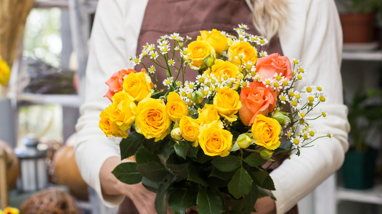 Woman holding yellow and orange flower bouquet