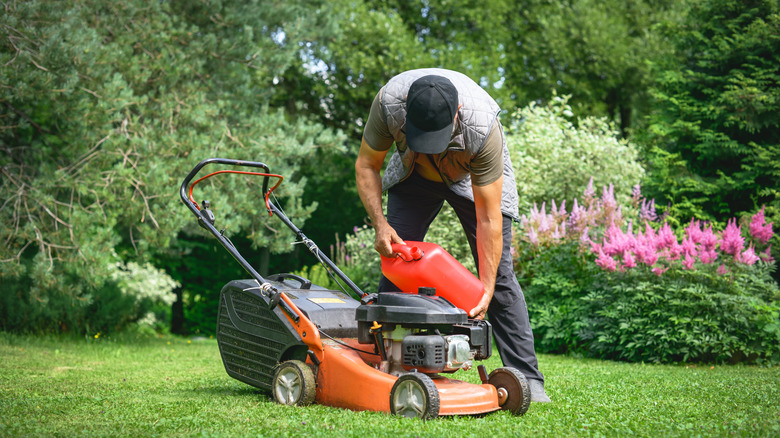 Man adding oil to mower