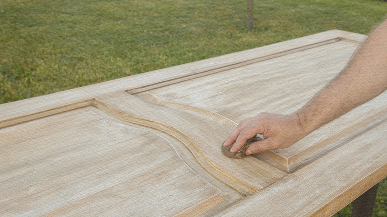 Person's hand refinishing door with a woodgrain look