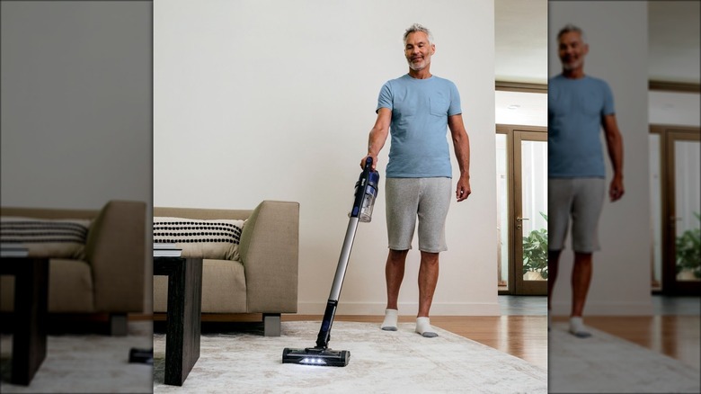 man using stick vacuum