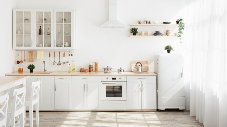 A home kitchen has a white interior design and wood detailing