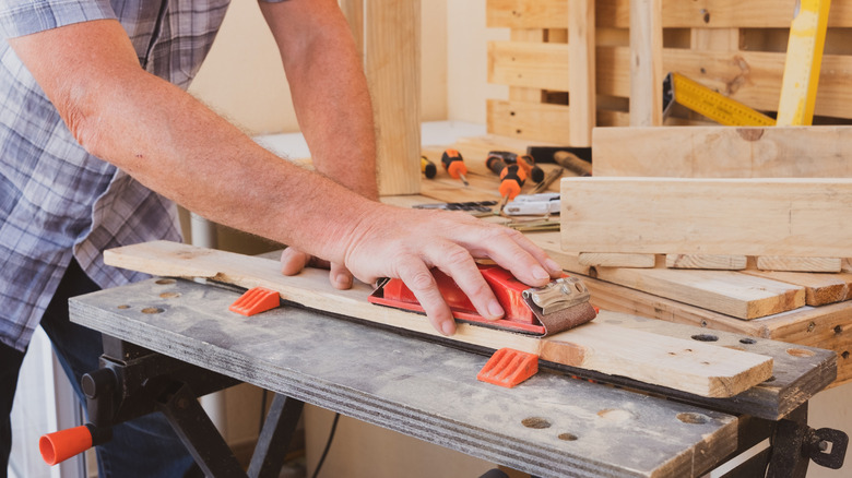 A man sands down wood pallets for a DIY project