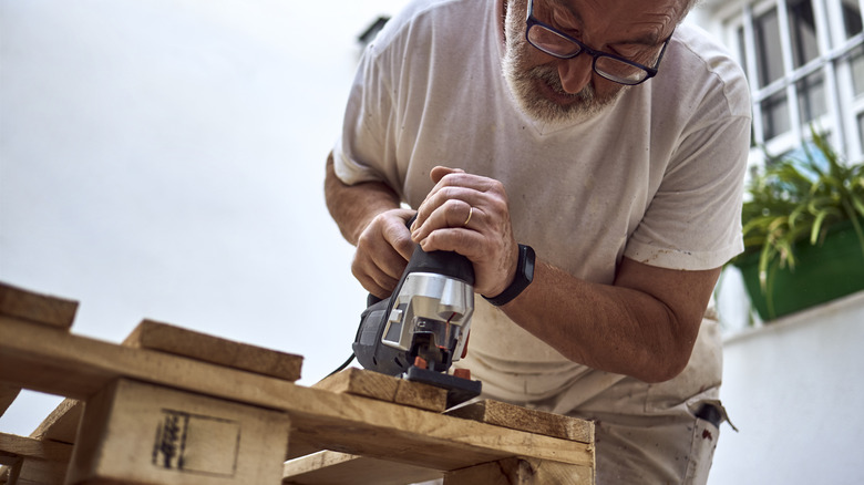 A man saws through a pallet to make a DIY workbench