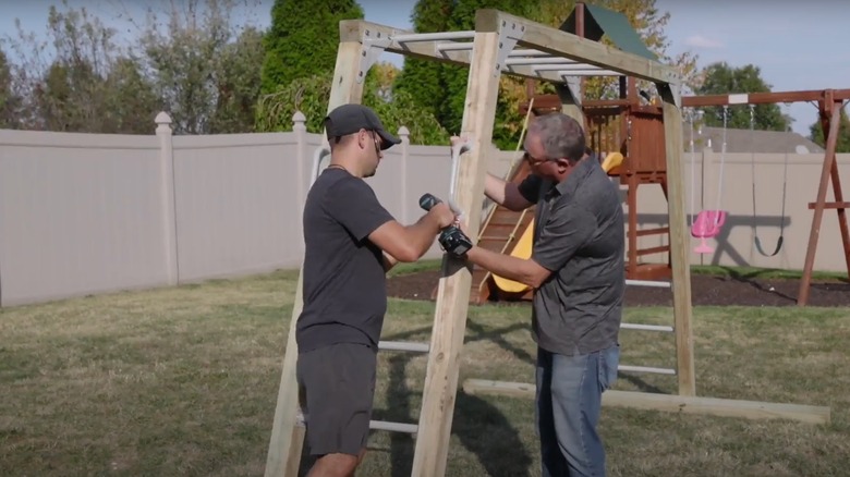 Men assembling monkey bar frame