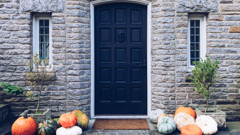 front porch with pumpkins and black door