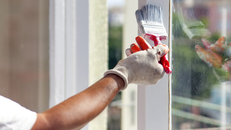 Person painting window trim