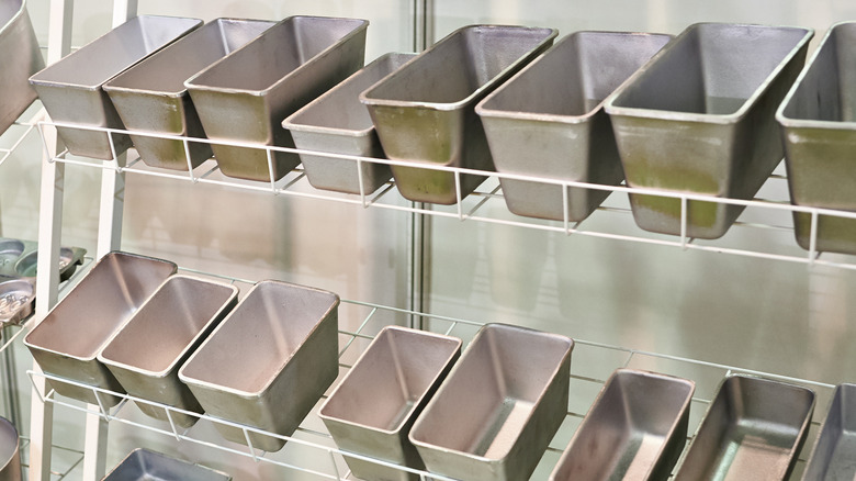 A selection of metal loaf pans for sale on the shelves of a baking supply store.