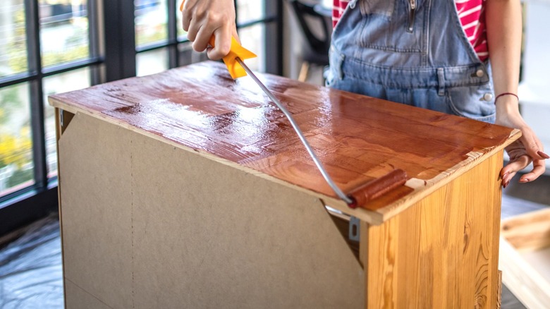 woman staining a wood cabinet top