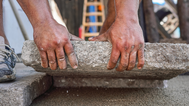 person laying pavers on the ground for a walkway