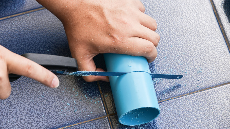 hands sawing PVC pipe