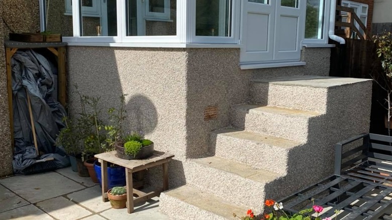 An exterior staircase and foundation adorned in pebbledash