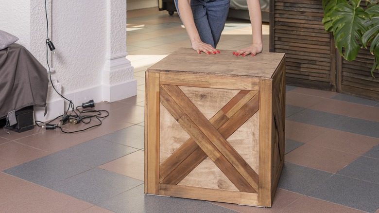 Woman pushing cube-shaped small table