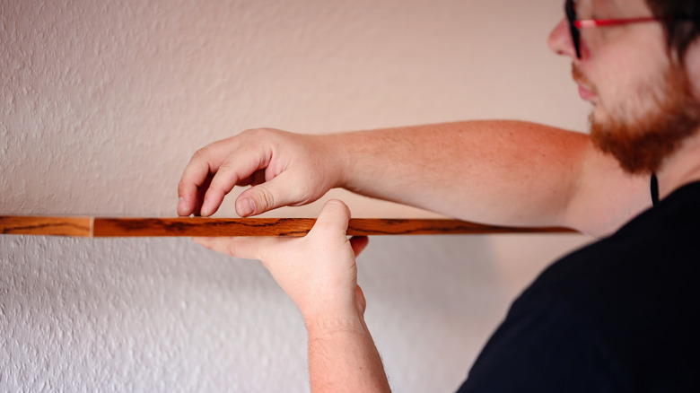 Man installing wooden open shelving