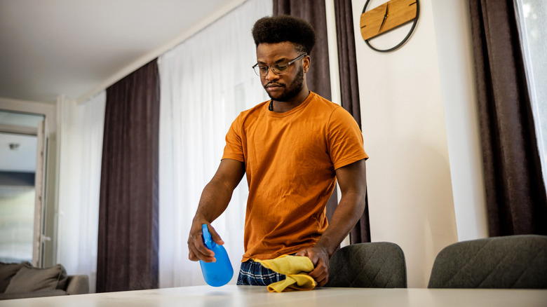 young man cleaning with spray