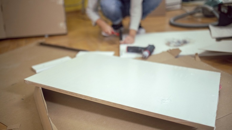 White particleboard furniture panel on packaging with person building in the background