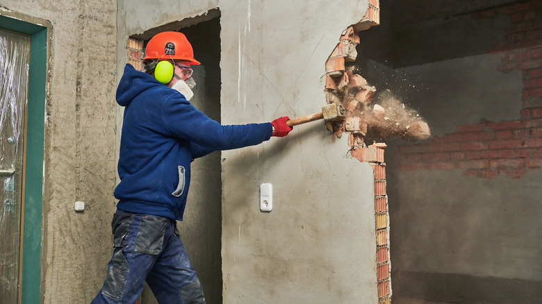 Person breaking wall, renovation demolition