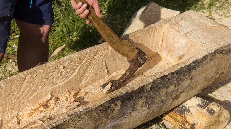 person using an adze on wood