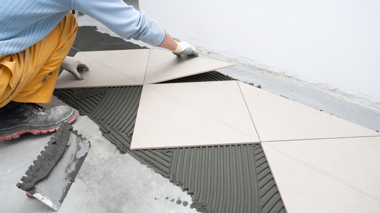 person installing white tile floor