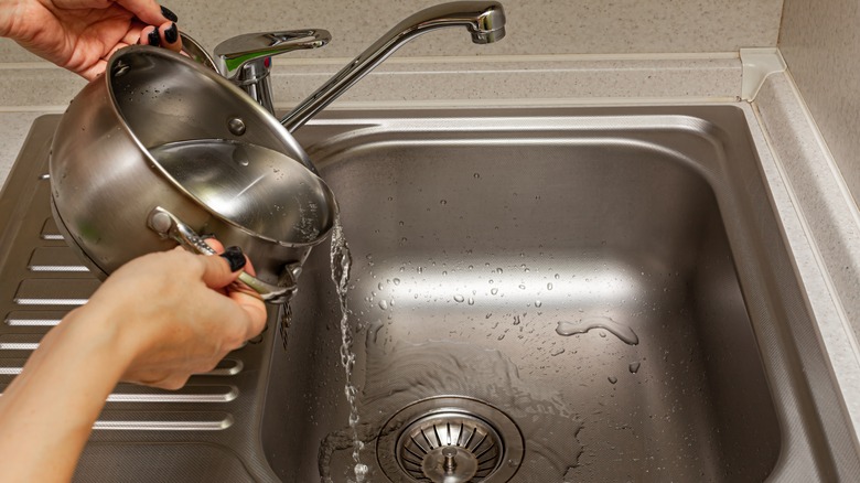 person pouring hot water in drain