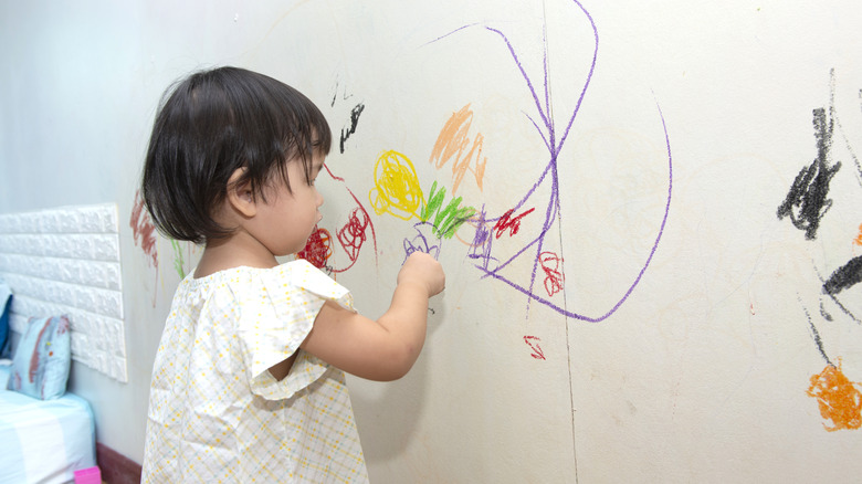 Child drawing with crayon on wall