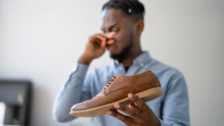 man holding smelly shoes