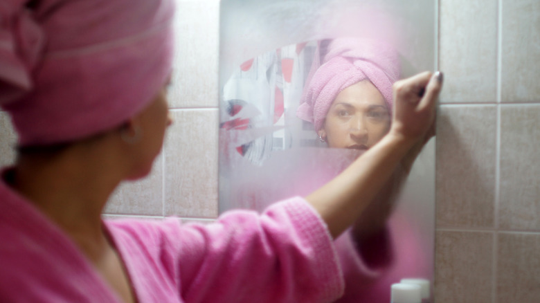 Woman wiping fog off a mirror