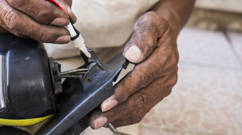 man gluing metal object together