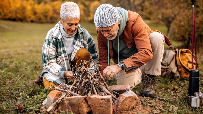 older couple lighting campfire outdoors