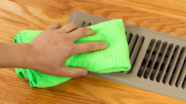 person wiping floor air vent