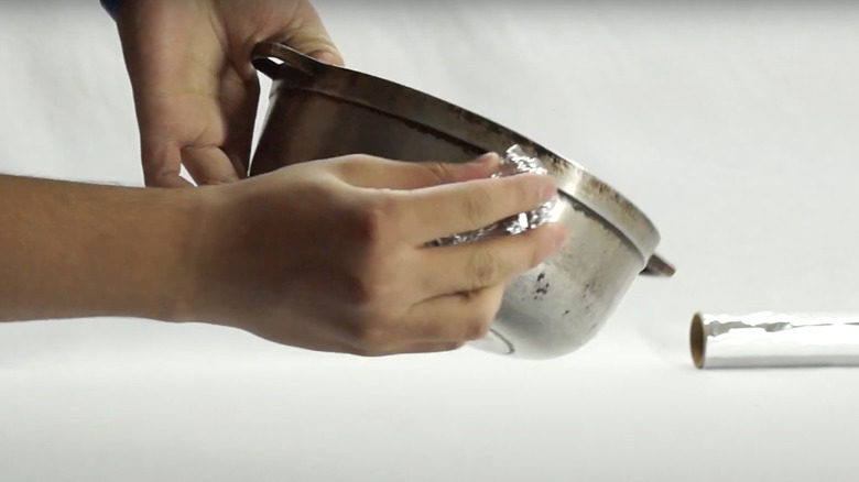 woman scrubbing stainless steel with aluminum foil