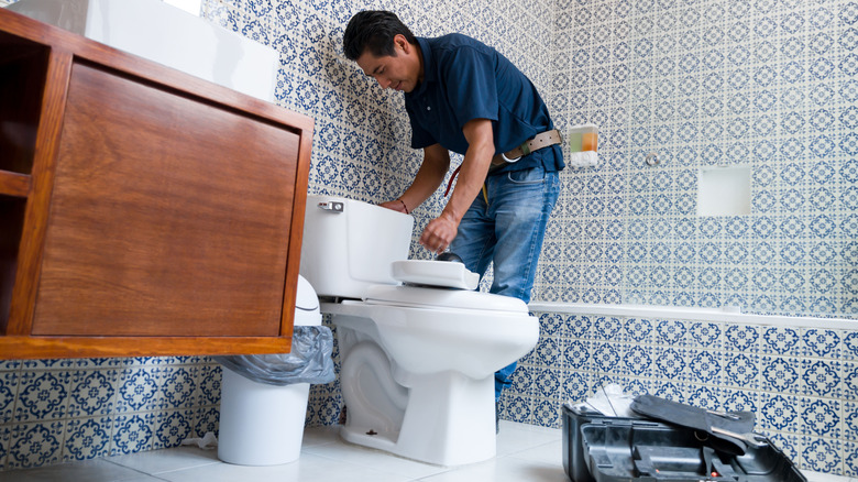 Plumber working on toilet