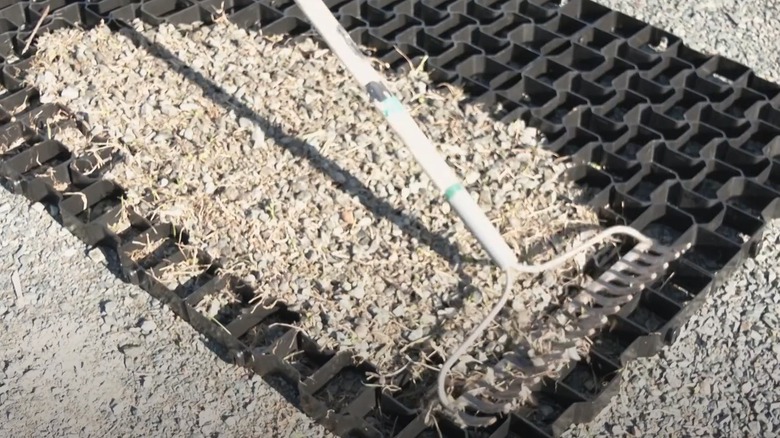 Person using a rake to spread gravel over the top of open-grid pavers