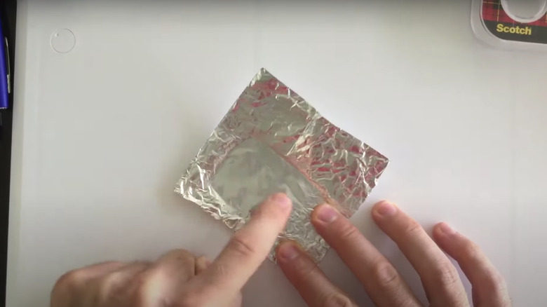 Person smoothing out aluminum foil