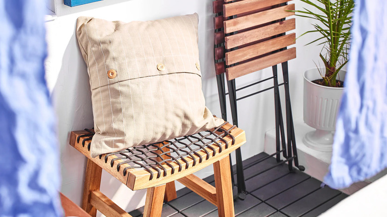 An IKEA STACKHOLMEN stool decorated with a cushion sits outside on a porch