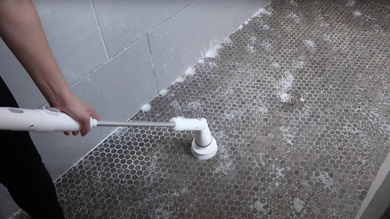 Woman cleans shower with electric scrub brush