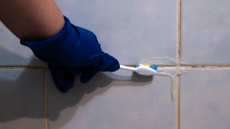 person cleaning grout with toothbrush