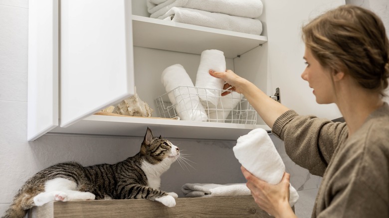 woman putting towels in cabinet