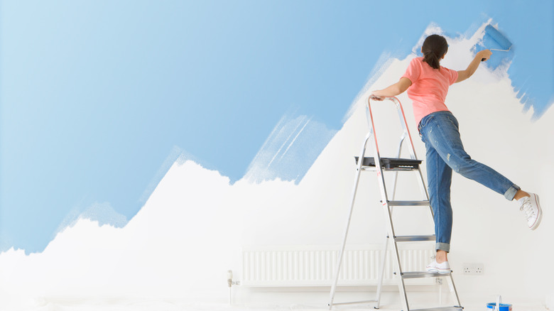 woman painting haphazardly on ladder