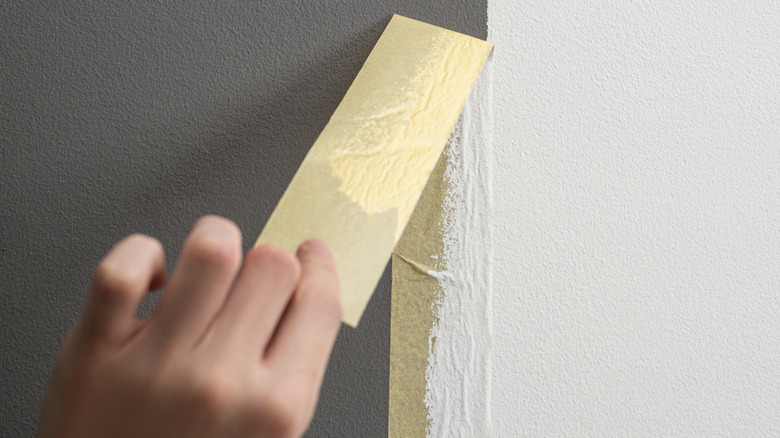 Person pulling tape off wall