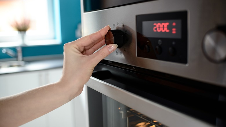 woman setting temperature on oven